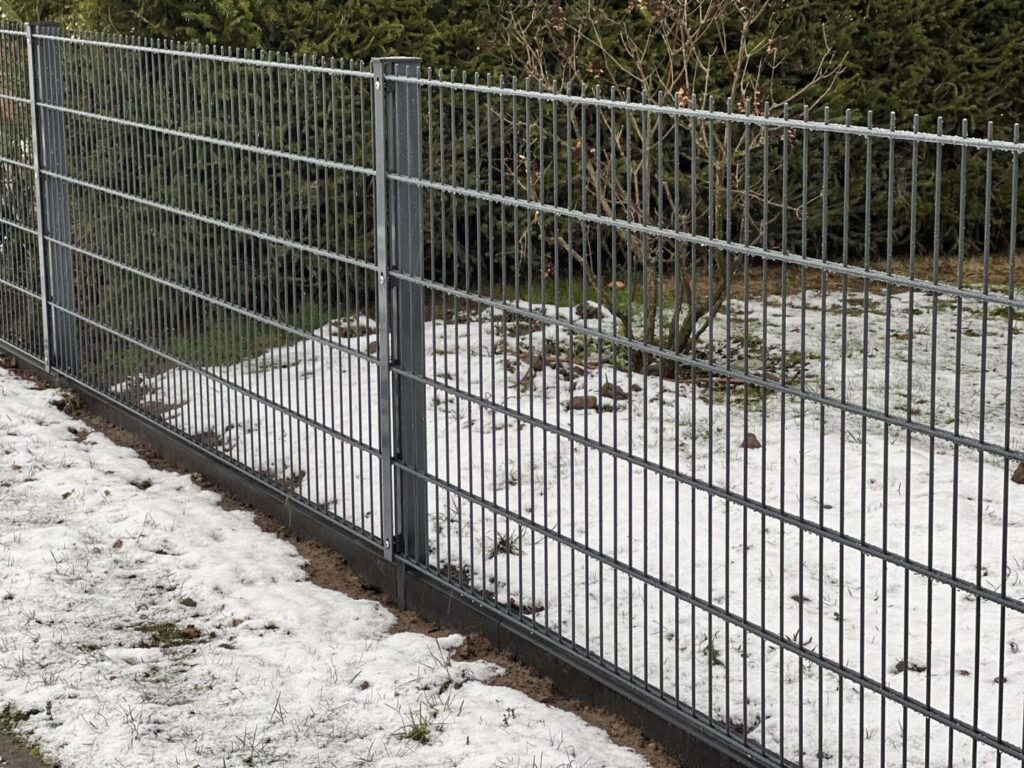 Metallzaun im Garten mit Schnee bedeckt