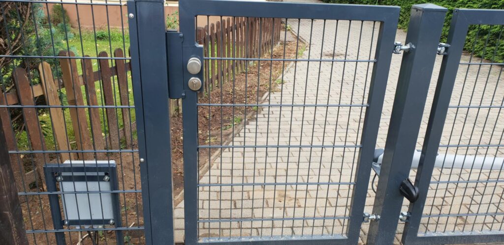 Metallgittertor mit Schloss und gepflastertem Weg