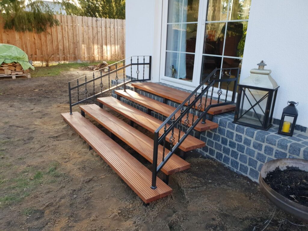 Holzterrasse mit Metallgeländer am Hauseingang