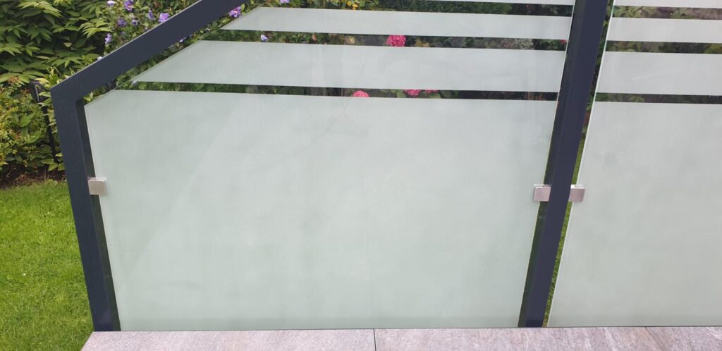 Mattglas Gartenzaun mit Metallrahmen und Blumen dahinter