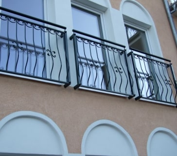 Eisengeländer an Hausfassade mit zwei Fenstern