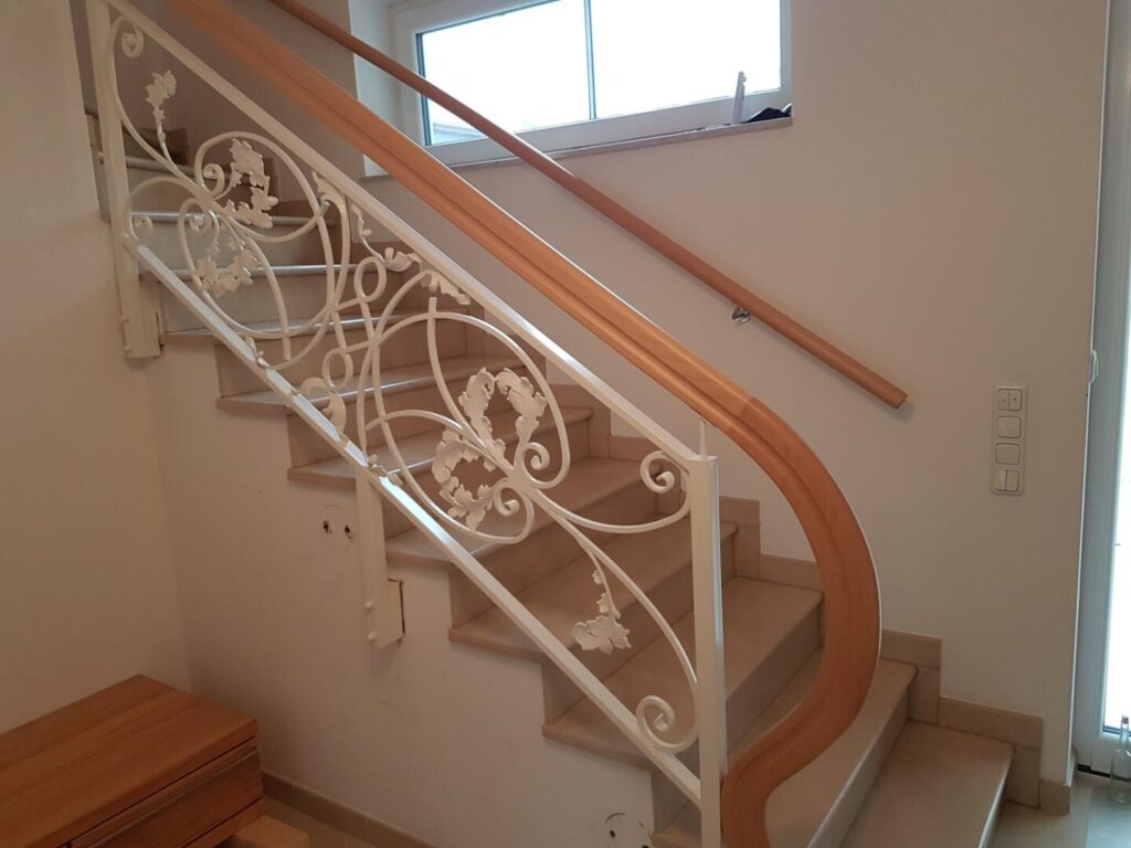 Treppe mit Holzgeländer und dekorativem weißen Metallgitter