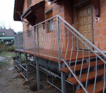 Metallgeländer mit Holzterrasse an Ziegelhaus