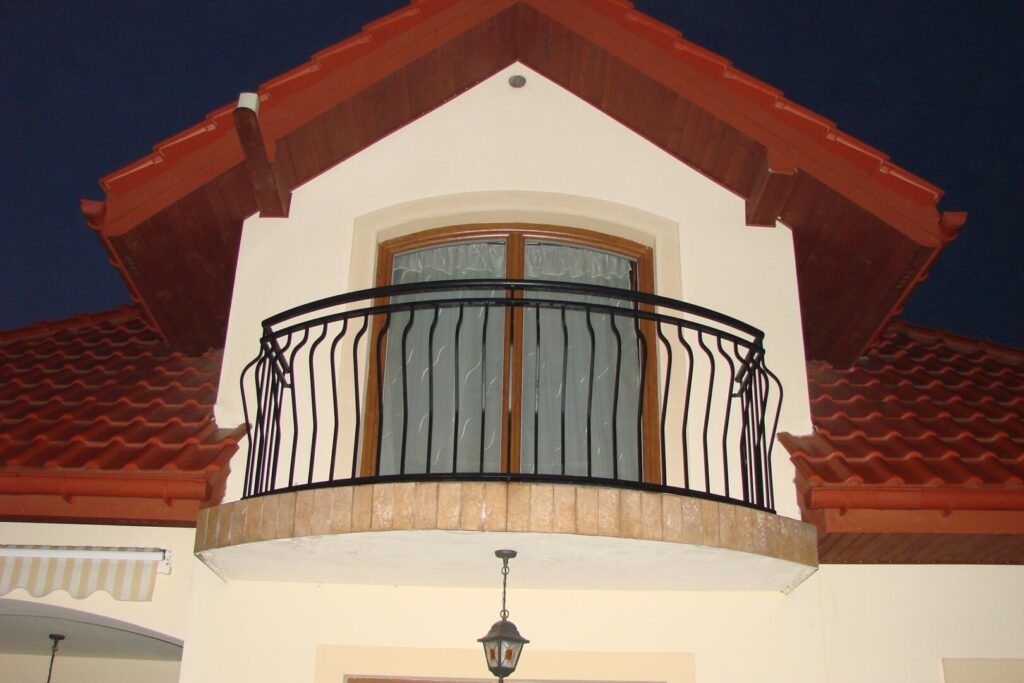 Kleiner Balkon mit schmiedeeisernem Geländer an Hausfassade