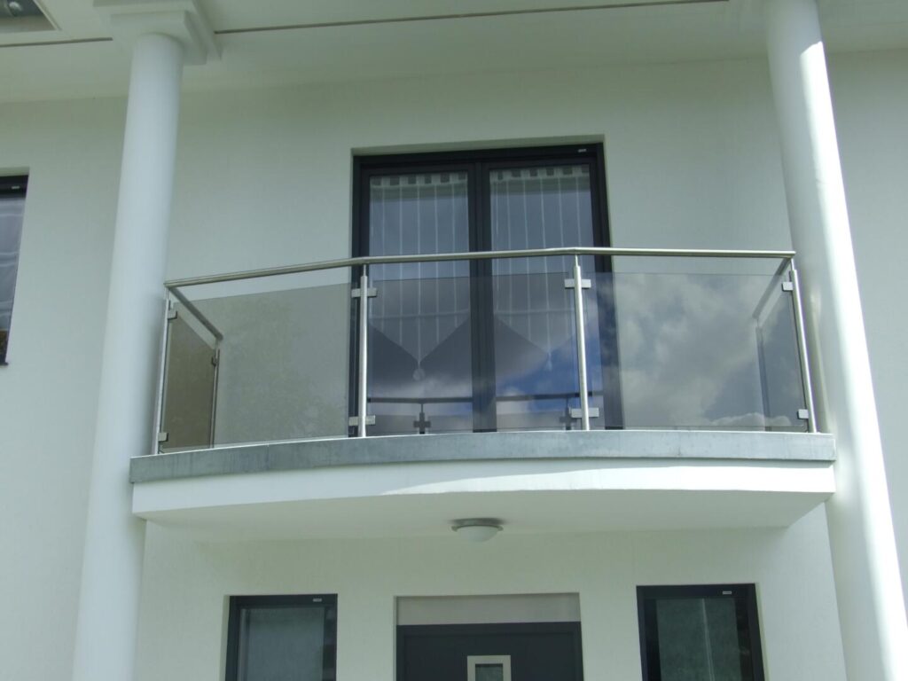 Moderner Balkon mit Glasgeländer am weißen Haus