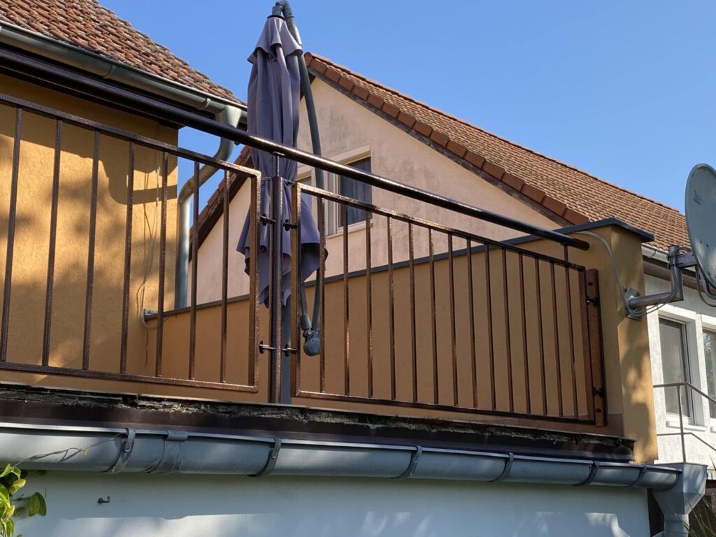 Balkon mit Metallgeländer und geschlossener Sonnenschirm
