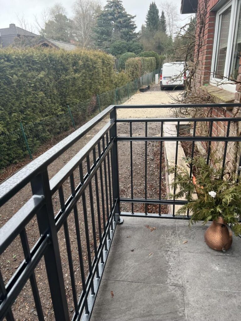 Balkon mit Metallgeländer und Blick auf Gartenweg