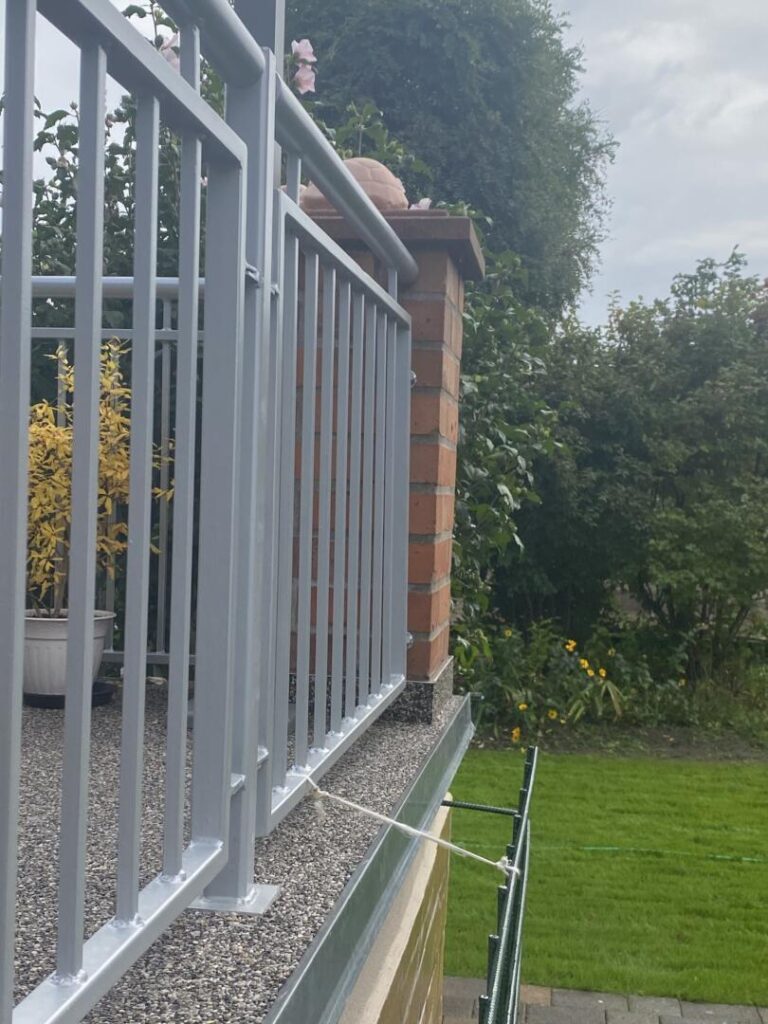 Metallgeländer auf Terrasse mit Garten im Hintergrund