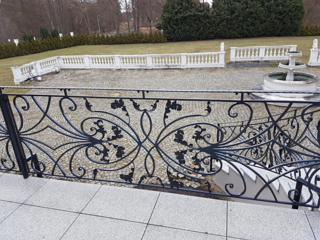 Verzierte Metallgeländer mit Brunnen und Gartenblick