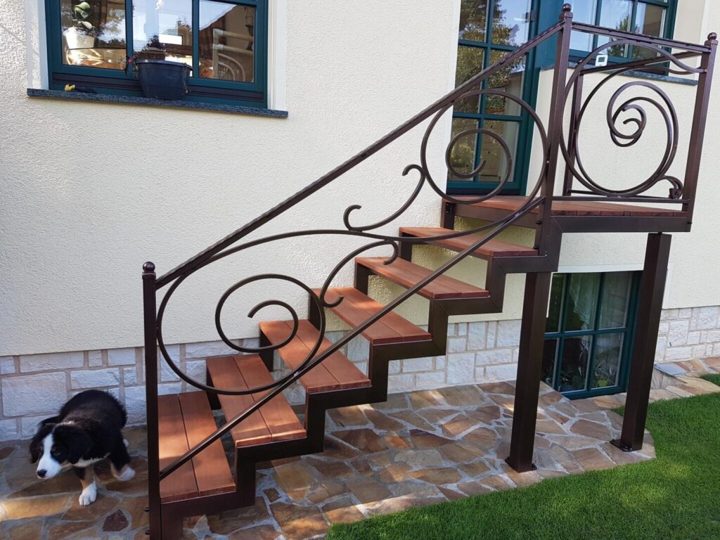 Außentreppe mit Holzstufen und dekorativem Metallgeländer