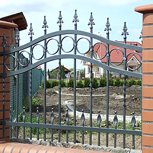 Geschmiedetes Gartentor zwischen Ziegelpfeilern