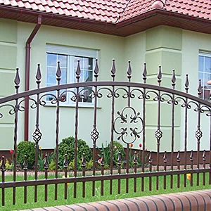 Metallzaun vor modernem Haus mit Garten