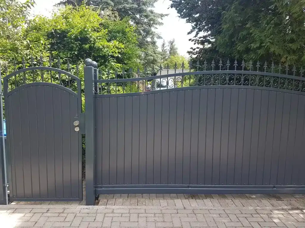 Graues Metalltor mit dekorativem Zaun im Garten