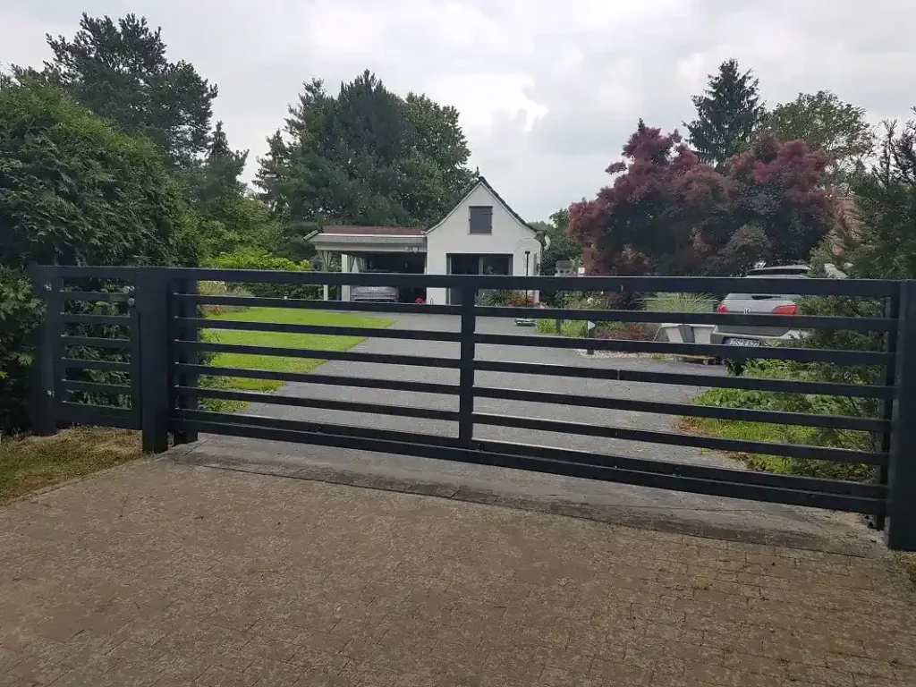 Modernes schwarzes Tor vor Einfamilienhaus mit Einfahrt