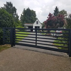 Moderne Metallzufahrtstor vor Einfahrt und Haus