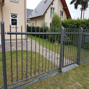 Grauer Metallzaun vor einem modernen Haus