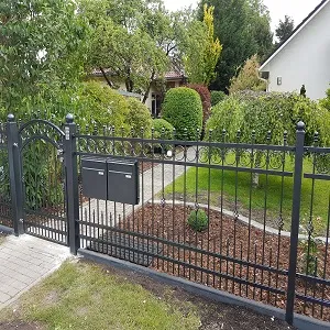 Metallzaun vor gepflegtem Hausgarten