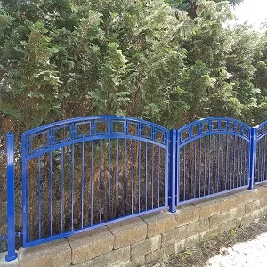 Blauer Metallzaun vor grünen Hecken