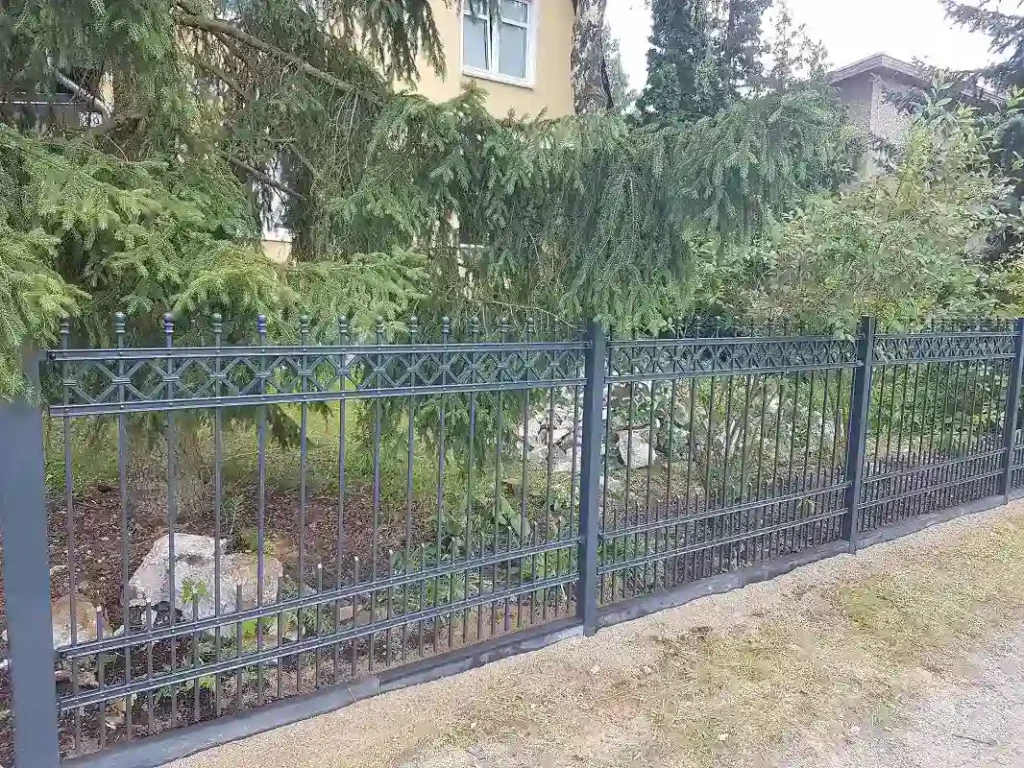 Schwarzer Metallzaun vor Garten und Haus