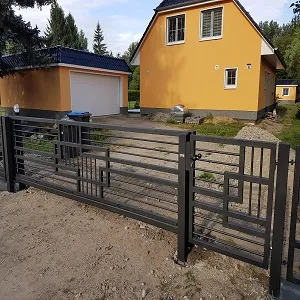 Modernes Metalltor vor gelbem Haus mit Garage