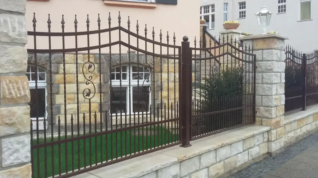 Schmiedeeiserner Zaun vor einem Steinhaus